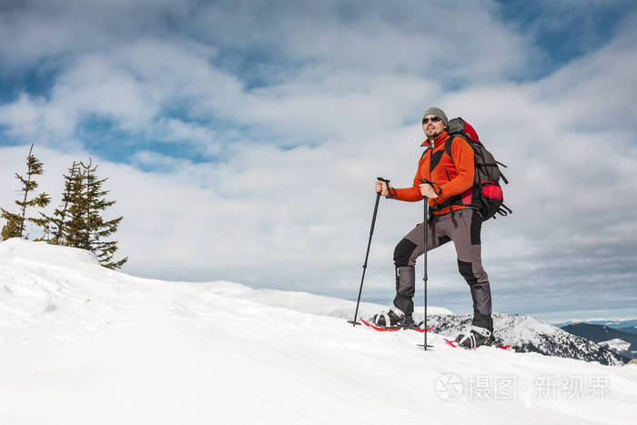 冬天爬山. 一个穿雪鞋的人正在爬到山顶. 冬天上升.