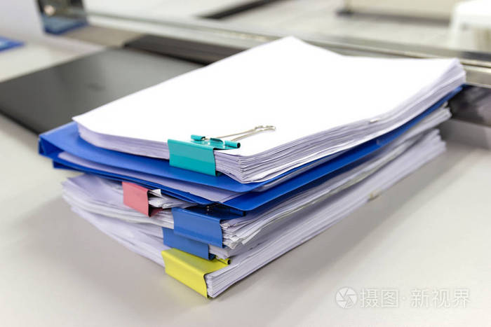 档案文件中的一叠纸文件在办公室的办公桌上有回形针的商业概念
