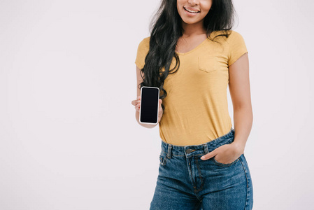 微笑的非洲裔美国女孩的照片显示智能手机与空白屏幕隔离在白色上