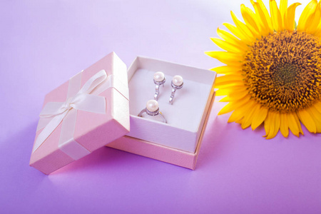 礼品盒中的珍珠首饰套装，紫色背景上的向日葵