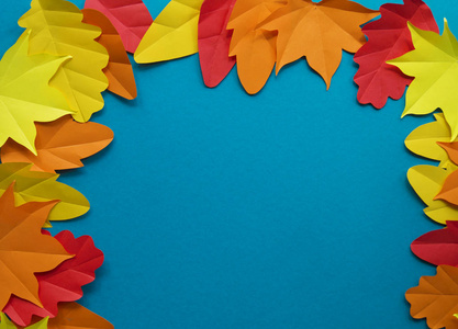 纸的叶子落红橙黄叶落。 蓝色背景。 手工折纸。