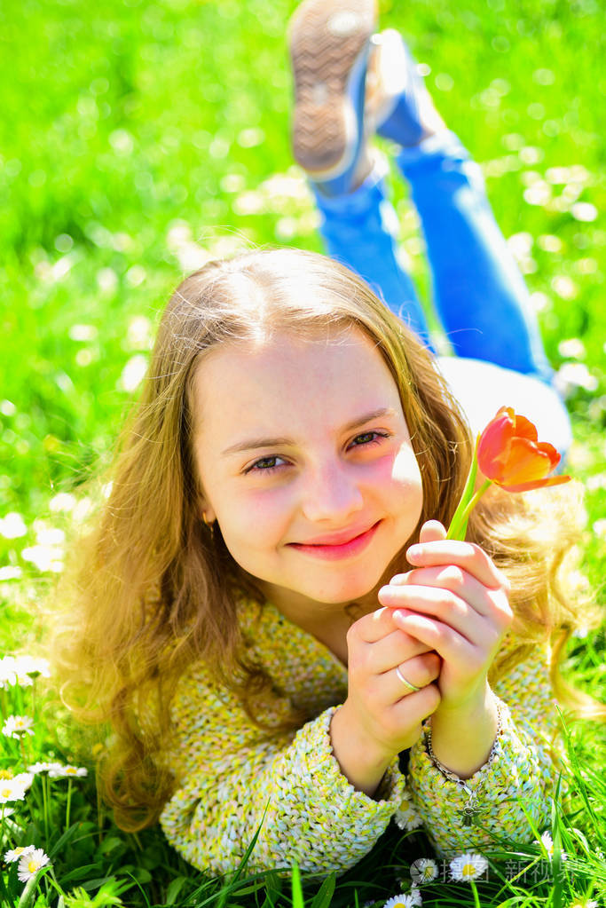 青春和无忧无虑的观念.孩子喜欢春天阳光明媚的日子, 而躺在草地上花.