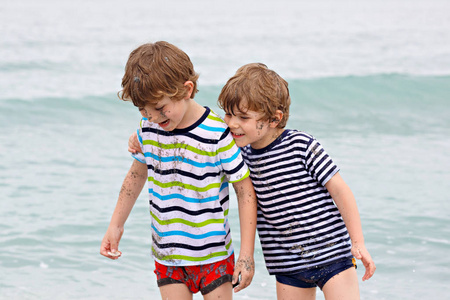 两个快乐的小男孩在海边奔跑。有趣的孩子, 兄弟姐妹, 双胞胎和最好的朋友做假期和享受夏天在暴风雨的雨天。迈阿密佛罗里达家庭肖像