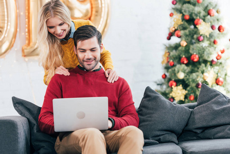 圣诞快乐的一对夫妇在家里一起使用笔记本电脑