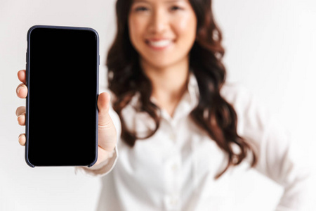 一位微笑的亚洲女商人展示了一部空白屏幕的手机