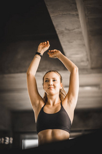 年轻的金发女人有吸引力的健身锻炼在健身房。 女人在健身俱乐部的机器跑步机上伸展肌肉和运动后放松。