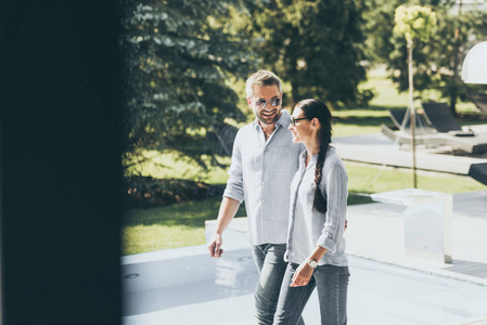 微笑的夫妇戴着太阳镜在乡间别墅散步
