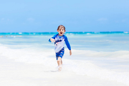 兴奋的孩子玩,在阳光下冲浪保护泳衣在海洋度假.