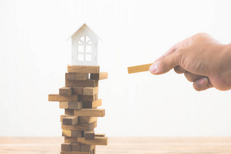 手拿木块与模型白宫在木块游戏。 房地产住房市场的投资风险和不确定性。 物业投资和房屋抵押金融理念。 复制空间。
