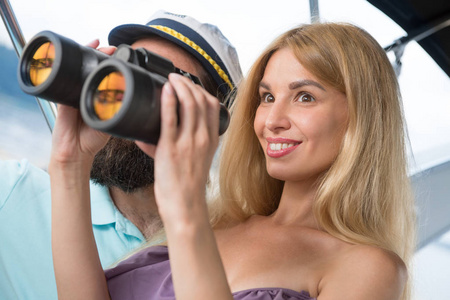 一个年轻人在游艇上用望远镜看着一个女孩