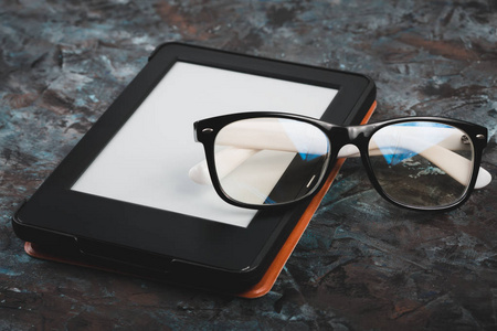 桌子上的电子书和纸质书，有一杯咖啡，一台笔记本电脑和阅读眼镜。自我教育的概念..