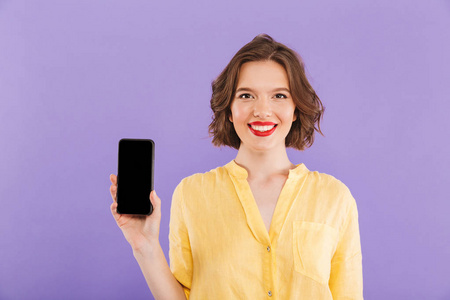 一位微笑的年轻女子的肖像，她在紫色背景下展示了一部空白屏幕手机