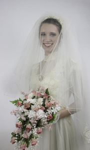 美丽的年轻新娘手持花束站着
