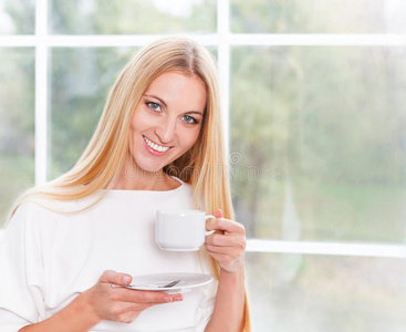 可爱的年轻女子在家喝茶的画像
