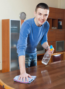 在客厅用清洁剂和抹布清洁家具的人照片