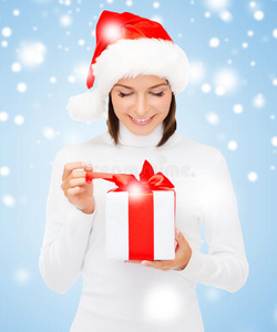 微笑的女人戴着圣诞老人的帽子和礼品盒