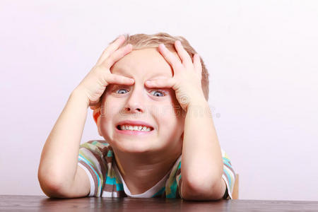 桌旁惊喜交集的情绪激动的金发男孩照片