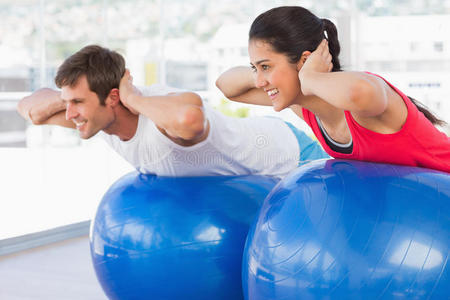 健身夫妻在健身房健身球上锻炼