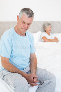 悲伤的老人躺在床上，妻子在背后