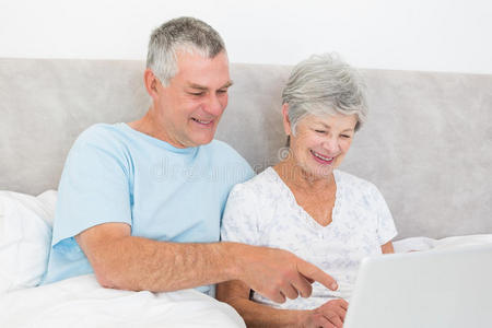 老年夫妇在床上使用笔记本电脑