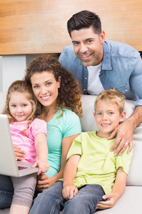 快乐家庭坐在沙发上用笔记本电脑