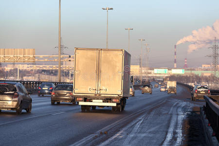 冬季日落时公路上行驶的卡车和汽车