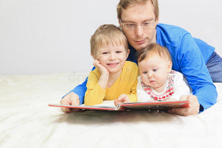 爸爸和两个孩子在床上看书