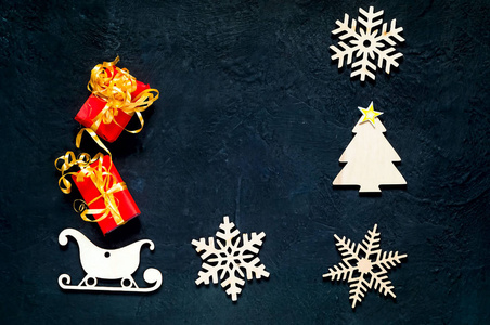 装饰木质圣诞雪花和雪橇。假日深蓝色背景与圣诞礼品盒, 顶部视图。平躺
