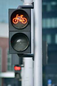 夏季城市背景下带有自行车图标和活动红色解析灯的自行车交通灯