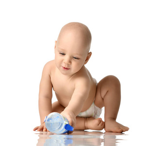 婴儿男婴婴儿男孩坐在裸尿布尝试采取一瓶水隔离在白色