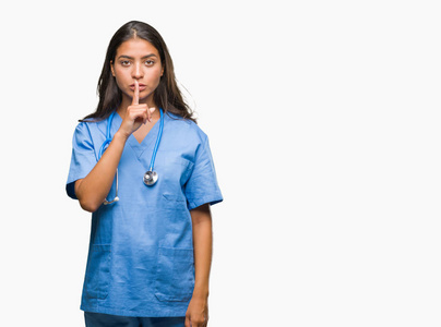 年轻的阿拉伯医生，外科医生，女人，在孤立的背景下，要求安静，手指在嘴唇上。 沉默和秘密的概念。