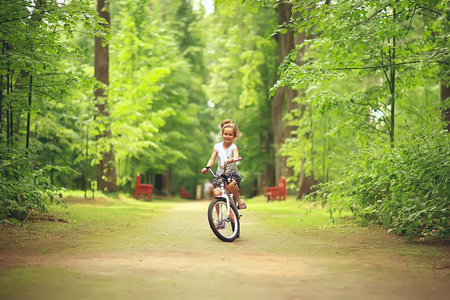 在夏天公园骑自行车的小女孩