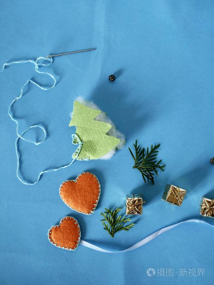 手工缝制一棵圣诞树这是用明亮的蓝色背景上的毛毡制成的针线心的装饰