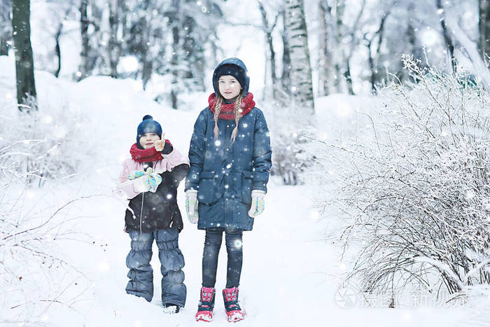 两个小女孩在冬季公园玩雪. 童年友谊,家庭的概念