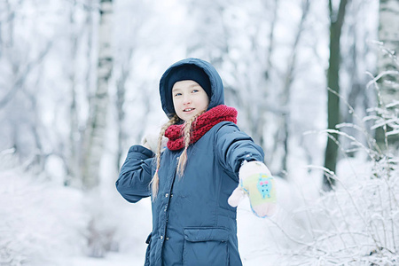 白雪皑皑的冬天公园里可爱的小女孩，一个穿暖和衣服的孩子的季节性照片