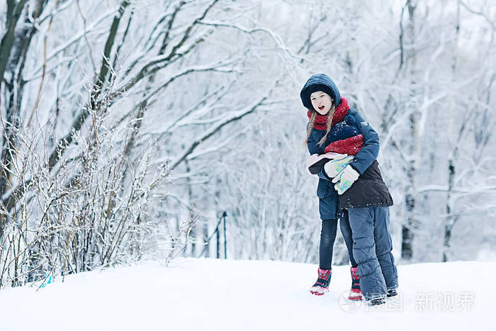 两个小女孩在冬季公园玩雪. 童年友谊,家庭的概念
