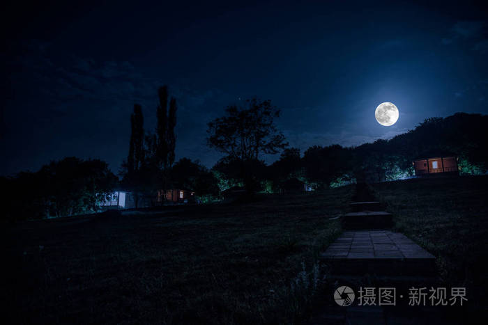 夜晚用月亮或老式乡村住宅在森林中建造的山夜景观,夜晚用云彩和星星.