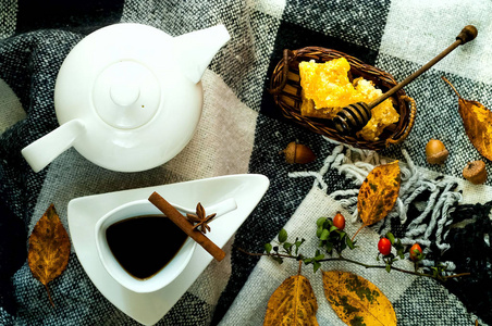 秋季家居装饰。白色陶瓷壶和葡萄酒杯, 茶, 肉桂棒, 八角和蜂蜜在蜂窝