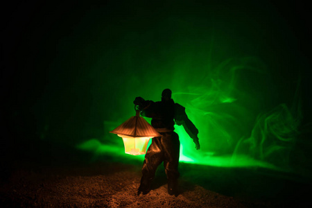 穿着雨衣的人来自黑暗的森林,手里拿着发光的灯笼.