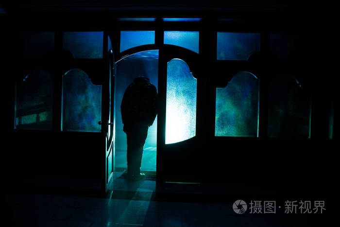 夜晚在窗户前的人类的轮廓. 可怕的场景万圣节概念模糊剪影的疯子.