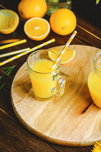 一杯鲜榨的橙汁和橘子在木桌上。秋天舒适质朴的心境静物