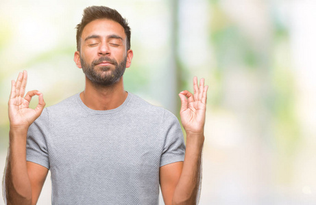 成年西班牙裔男子在孤立的背景下放松和微笑，闭着眼睛做冥想手势与手指。 瑜伽概念。