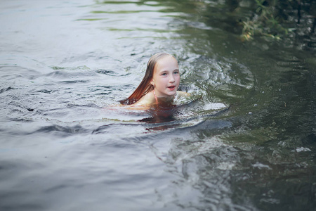 可爱的小女孩在池塘里游泳