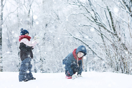 两个小女孩在冬季公园玩雪。 童年友谊家庭的概念