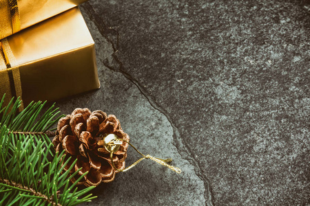 圣诞背景。 金色礼盒圣诞树枝和圆锥形石板背景复制空间