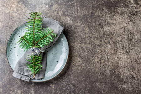 节日圣诞食品背景餐具餐巾纸与戒指和圣诞树树枝桌子设置在银色色调的石头背景。