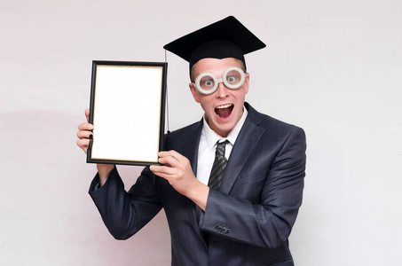 研究生戴着帽子,手里拿着灰色背景上孤立的文凭证书. 教育观念.照片