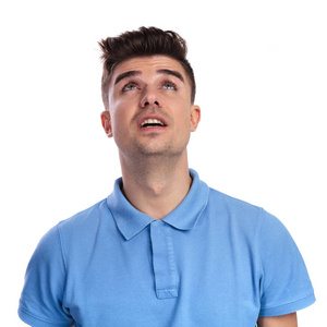 年轻的休闲男子抬头看白色背景的东西照片