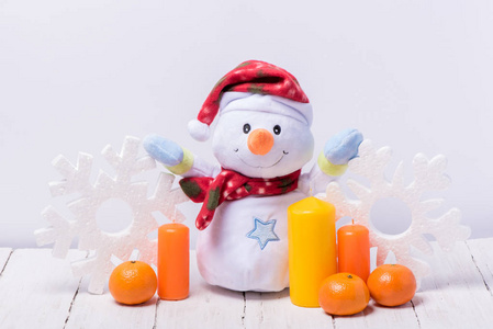 在白色的木制背景上，有橙色曼陀罗和蜡烛的有趣的雪人