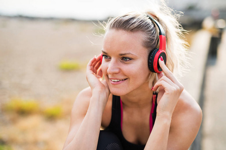 一个特写的年轻女子赛跑者用耳机休息在海外面